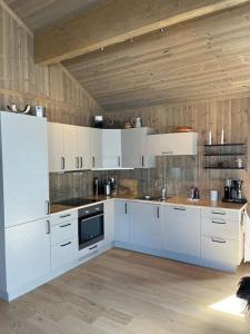 a kitchen with white appliances and a wooden ceiling at Hovdetunet 77-Gaustablikk in Gaustablikk