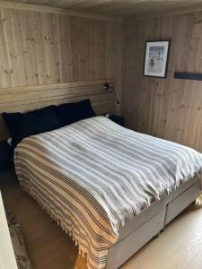 a bedroom with a bed with a striped blanket on it at Hovdetunet 77-Gaustablikk in Gaustablikk