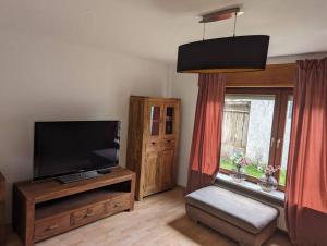 a living room with a flat screen tv and a window at Heufelsen Ferienwohnung in Hinterweidenthal
