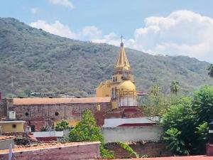 une église avec une cloche d'or au-dessus d'un bâtiment dans l'établissement Departamento para seis personas en Etzatlán., à Etzatlán