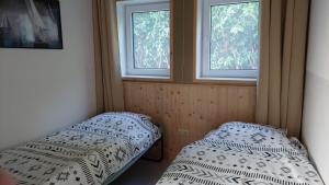 twee bedden in een kamer met twee ramen bij Huisjedelinde in Wolvega