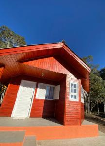 a small red building with white doors on it at Chalés Canto da Serra in Monte Verde