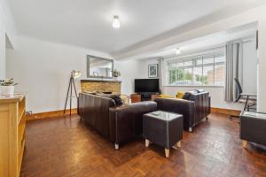 a living room with leather furniture and a television at 5 double beds in a detached house in Cheshunt in Cheshunt