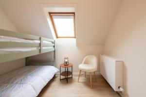 ein kleines Schlafzimmer mit einem Etagenbett und einem Stuhl in der Unterkunft De Burg in Alveringem