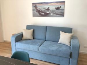 a blue couch in a living room with a painting at Charme Apartments in Trapani