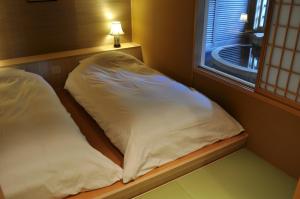 two beds sitting next to a window in a room at Jozankei Daiichi Hotel Suizantei in Jozankei