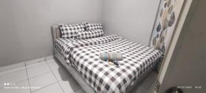 a small bed with a black and white checkered blanket at CITRA INN in Tangerang