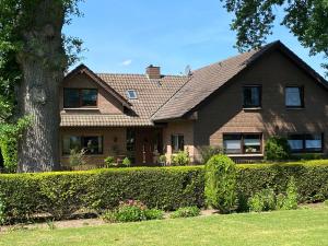 a brown house with a tree and bushes at Grenzblick in Isselburg-Anholt in Isselburg