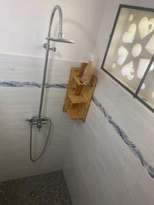 a bathroom with a shower and a wooden shelf at Villa Caïmite in Rémire-Camp