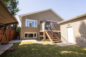 a house with a staircase in a yard at Lux Haven, Sleeps 8, AC, Balcony, Close to YQL in Lethbridge