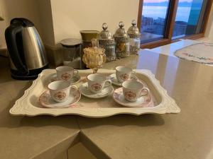 a tray with tea cups and saucers on a counter at Deniz Manzaralı Sümela Evleri in Akcaabat