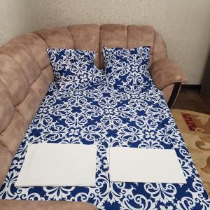 a couch with a blue and white blanket on it at Сдаётся в 2-х ком.кв. 1 комната на берегу моря на 2 человека. Проживание с хозяевами. in Pizunda