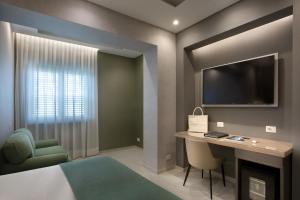 a room with a bed and a desk and a tv at Montespina Park Hotel in Naples