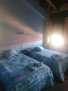 Habitación con 2 camas y una luz en la pared. en ALBERGUE peregrinos CASAFLOR, en Murias de Rechivaldo