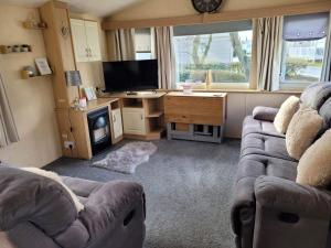 a living room with a couch and a desk and a television at Chestnut grove, Thorpe park in Humberston