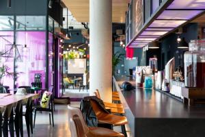 a restaurant with a bar with chairs and tables at Moxy Essen City in Essen