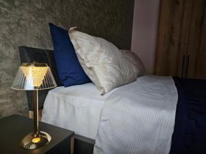 a bed with a pillow and a lamp on a table at Sun&Moon Apartments in Novi Sad