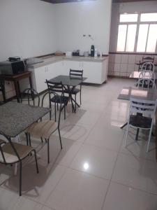 a room with tables and chairs and a kitchen at ORSI HOTEL in Araguari