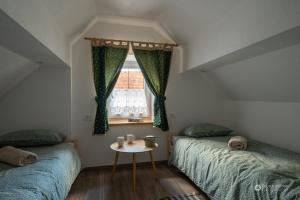 two beds in a room with a table and a window at Cherry house - cosy house - ideal for bear watching, in the neighborhood of the medieval Snežnik castle in Stari Trg pri Ložu