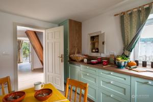 a kitchen with blue cabinets and a table with a dining room at Cherry house - cosy house - ideal for bear watching, in the neighborhood of the medieval Snežnik castle in Stari Trg pri Ložu