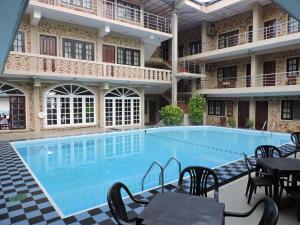 a swimming pool with tables and chairs next to a building at Oasis Beach Resort in Negombo