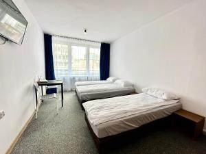 trzy łóżka w pokoju ze stołem i oknem w obiekcie BLUE Hostel - Private Rooms by Friendly Hostel w Poznaniu