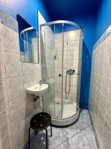 ein Bad mit einer Dusche, einem Waschbecken und einem Stuhl in der Unterkunft BLUE Hostel - Private Rooms by Friendly Hostel in Posen