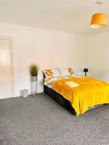 a bedroom with a large bed with a yellow blanket at Private Room close to Leeds University and City centre in Leeds