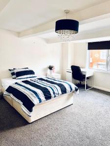 1 dormitorio con cama, escritorio y lámpara de araña en Private Room close to Leeds University and City centre, en Leeds