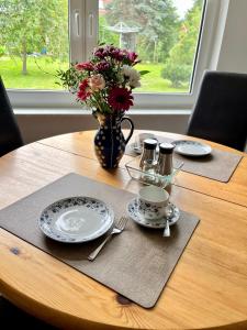 a wooden table with plates and a vase of flowers at Ferienhaus Ankerplatz in Lambrechtshagen