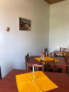 una sala da pranzo con tavoli in legno e tovaglioli gialli di Art House Hostel Aleksandr a Kutaisi