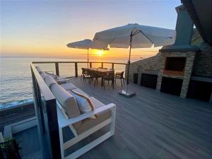 a deck with a table and chairs and an umbrella at Ocean Front in Paul do Mar