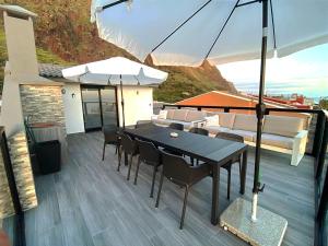 une terrasse avec une table, des chaises et un parasol dans l'établissement Ocean Front, à Paul do Mar