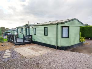 a green tiny house sitting on top of a yard at Lake District Holiday Home, near Ennerdale Lake - Inglenook 06 - Free Wifi in Workington
