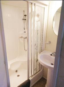 a white bathroom with a shower and a sink at Lake District Holiday Home, near Ennerdale Lake - Inglenook 06 - Free Wifi in Workington