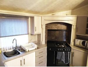 a kitchen with a sink and a stove top oven at Lake District Holiday Home, near Ennerdale Lake - Inglenook 06 - Free Wifi in Workington