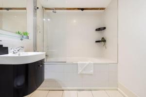 uma casa de banho branca com um lavatório e um chuveiro em Wild Roses Serviced Apartments - ExCel Warehouse 2 em Londres