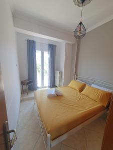 a bedroom with a bed with yellow sheets and a window at Helen's studio in Myrina