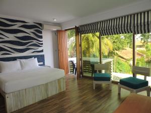 a bedroom with a bed and a balcony with a table at Binnacle Negombo in Negombo