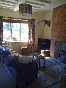 een woonkamer met een bank en een open haard bij Characterful stone cottage in Uffington 