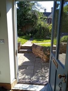 een open deur naar een tuin met een loopbrug bij Characterful stone cottage in Uffington 