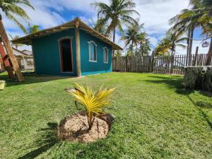 uma pequena casa azul num quintal com uma palmeira em Nuhatê Casa Hotel em Caraíva