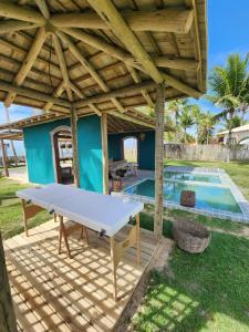 uma mesa de pingue-pongue debaixo de uma pérgula ao lado de uma piscina em Nuhatê Casa Hotel em Caraíva