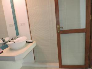 a bathroom with a sink and a glass shower door at Binnacle Negombo in Negombo