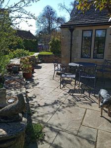 een patio met een tafel en stoelen en een hond bij Characterful stone cottage in Uffington 