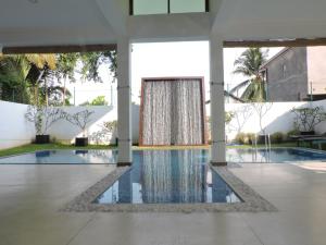 a swimming pool with a fountain in a building at Binnacle Negombo in Negombo