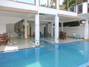 a house with a swimming pool and tables and chairs at Binnacle Negombo in Negombo