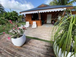 a wooden deck with two chairs and a house at Kaz bleu karaibes in Sainte-Anne