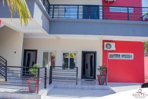 une maison avec une porte d'entrée rouge et des escaliers dans l'établissement Benteh 2, à Banjul