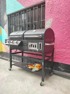 a grill on a cart in front of a pink wall at Baku Laureles Hostel in Medellín